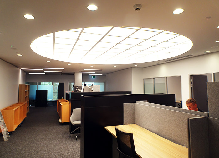 A contemporary office with a large skylight over the workstations.