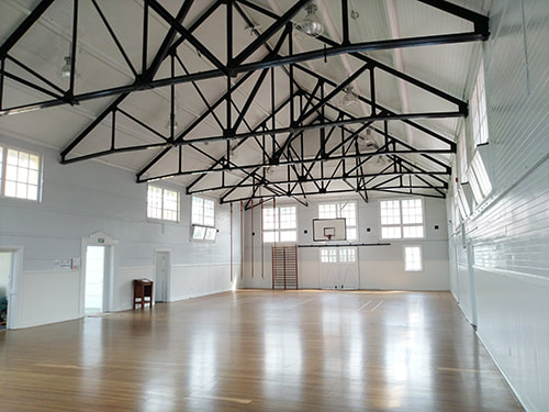 A large hall with white walls and exposed beams, it is light and airy.