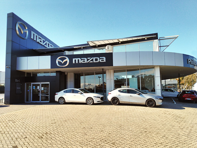 The showroom of Slaven Mazda - a modern architectural building with cars lined up outside.